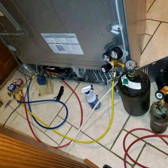 Gas manifold gauges connected during fridge diagnostics