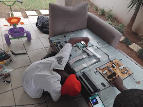Technicians repairing a flat screen TV on the floor